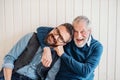 A portrait of adult hipster son and senior father sitting on floor indoors at home. Royalty Free Stock Photo