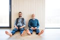A portrait of adult hipster son and senior father sitting on floor indoors at home. Royalty Free Stock Photo