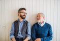 A portrait of adult hipster son and senior father sitting on floor indoors at home. Royalty Free Stock Photo