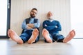 A portrait of adult hipster son and senior father sitting on floor indoors at home. Royalty Free Stock Photo