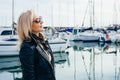 Portrait of an adult lady in sunglasses standing in a marina on yachts background Royalty Free Stock Photo