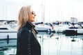 Portrait of an adult lady in sunglasses standing in a marina on yachts background. Royalty Free Stock Photo