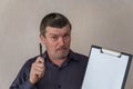 Portrait of an adult male holding a clipboard and pen. Man with short haircut and graying hair. White blank piece of paper Royalty Free Stock Photo