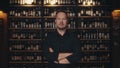 Portrait of an adult male restaurateur against the background of the wine shelves of an expensive restaurant. The