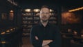 Portrait of an adult male restaurateur against the background of the wine shelves of an expensive restaurant. The