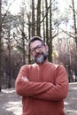 Portrait of adult man with crossed arms in a forest woods with trees and sunlight in background. Concept of people and nature. Royalty Free Stock Photo