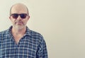 Portrait of an adult man with a gray beard with dark glasses shirt on a light background, toned.