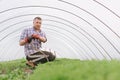 Portrait of an adult man in a greenhouse, watering plants from the hose. Farmer takes care of seedlings in the home greenhouse. Royalty Free Stock Photo