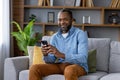 Portrait of adult mature man, African American man smiling and looking at camera with phone in hand, happy sitting on Royalty Free Stock Photo