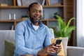 Portrait of adult mature man, African American man smiling and looking at camera with phone in hand, happy sitting on Royalty Free Stock Photo