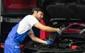 Portrait Adult Professional handsome male mechanic wearing uniform, fix, repair, check, inspect car engine, filling lubricant,