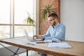 Portrait of adult serious male company director sitting in comfortable office, checking company profits on laptop Royalty Free Stock Photo