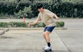 Portrait adult sportive Asian skater wearing hipster shirt with shorts, smiling with happiness, standing on skateboard and playing