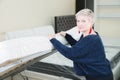 Portrait. Adult stylish woman, short-cut blonde, chooses a large orthopedic bed with a lifting mattress in a furniture Royalty Free Stock Photo