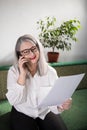 Portrait of an adult woman entrepreneur with grayish hair in a managerial position, dressed in a white blouse and busy working in