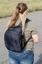 Portrait of an adult woman with long loose hair. Woman standing with a black shoulder bag. Outside. Rear view. Selective focus