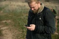 Portrait of an adventurer man using smartphone while hiking, searching for signal, or looking for direction on the steeppe. A Royalty Free Stock Photo