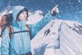 Portrait of adventurous young man on winter mountain top view pointing out. Snowboarders walking uphill for freeride