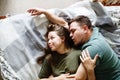 Portrait of affectionate embracing couple in casual clothes lying on a bed together, stay home concept