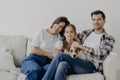 Portrait of affectionate family cuddle and sit together at couch in living room, change their home, have happy expressions. Father