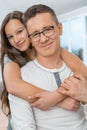 Portrait of affectionate girl embracing father from behind at home