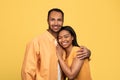 Portrait of affectionate young black couple embracing and looking at camera over yellow studio background Royalty Free Stock Photo