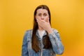 Portrait of afraid shocked young caucasian woman 25s wearing denim jacket covering mouth with palm, keep secret, does not tell Royalty Free Stock Photo