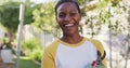 Portrait of african amercian woman holding secateur looking to camera and smiling in garden