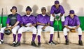 Portrait of african american baseball players sitting side by side in dugout