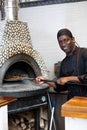 Portrait of african american chef man baking pizza in oven Royalty Free Stock Photo