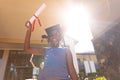 Portrait of african american elementary schoolboy wearing mortarboard showing degree on sunny day