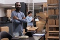 Portrait of african american employee standing with arm crossed in warehouse while working at customers packages