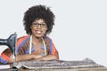 Portrait of an African American female fashion designer with sewing machine and cloth over gray background Royalty Free Stock Photo