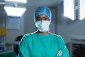 Portrait of african american female surgeon wearing surgical gown and face mask in operating theatre Royalty Free Stock Photo