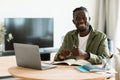 Portrait of african american freelancer guy sitting at desk at home office, looking at camera and smiling, free space Royalty Free Stock Photo
