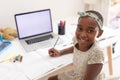 Portrait of african american girl at desk using laptop with copy space for online school lesson Royalty Free Stock Photo