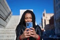 Portrait of an African-American girl with dreadlocks in her hair sending messages with her cell phone. Concept of technology Royalty Free Stock Photo