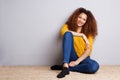 African american girl sitting on floor and smiling by gray wall Royalty Free Stock Photo
