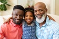 Portrait of african american grandfather, father and granddaughter smiling sitting on couch at home Royalty Free Stock Photo