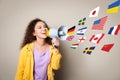 Portrait of African American interpreter with megaphone and flags of different countries on beige background