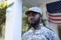 Portrait of african american male soldier standing in front of american flag outside home Royalty Free Stock Photo