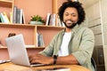 Portrait of African-American male student posing in the library, curly handsome guy using laptop Royalty Free Stock Photo