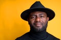 Portrait of an African American man in a black turtleneck and hat. Isolated on yellow background Royalty Free Stock Photo