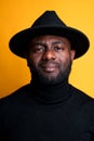 Portrait of an African American man in a black turtleneck and hat.  on yellow background Royalty Free Stock Photo