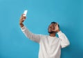 Portrait of an African-American man taking a selfie and smiling on a blue isolated background Royalty Free Stock Photo