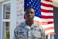 Portrait of african american mid adult army soldier in camouflage clothing standing against flag Royalty Free Stock Photo