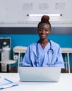 Portrait of african american nurse using laptop at white desk Royalty Free Stock Photo