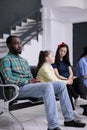 Portrait of african american patient looking tired waiting in busy hospital reception room Royalty Free Stock Photo