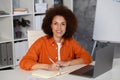 Portrait of African American successful woman entrepreneur with laptop in modern office, looking at the camera and smiling Royalty Free Stock Photo