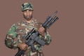 Portrait of African American US Marine Corps soldier holding M4 assault rifle over brown background